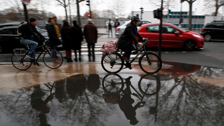 Bicycles riders are reflected in the water in Paris on December 7, 2019.